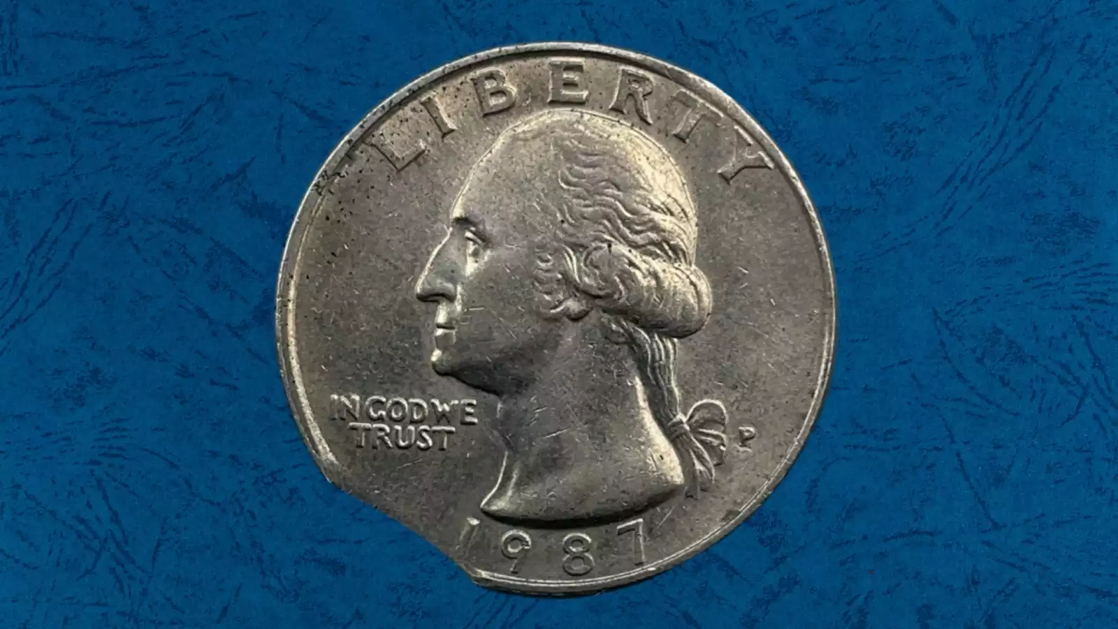 1987-P Washington Quarter off-center strike error showing Washington's portrait shifted to one side with a large blank crescent of unstruck metal on the opposite edge